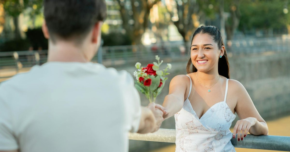 Young couple exchanging roses by the riverside in Buenos Aires, capturing a romantic moment.